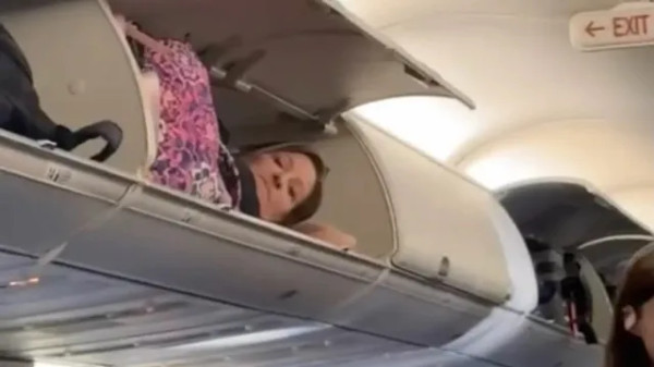 Mulher viraliza ao dormir em compartimento de bagagem de avião; VEJA VÍDEO