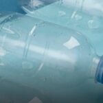 Garrafas plásticas descartadas podem se tornar matéria-prima para a produção de medicamentos, segundo estudo publicado nesta segunda-feira (16/3), na revista científica Nature Sustainability. A pesquisa mostrou que resíduos de plástico do tipo PET — material usado em garrafas e embalagens — podem ser convertidos em L-DOPA, um dos principais remédios usados no tratamento da doença de Parkinson. A descoberta foi feita por pesquisadores da Universidade de Edimburgo, no Reino Unido. No experimento, os cientistas utilizaram bactérias geneticamente modificadas para transformar moléculas derivadas do plástico em compostos usados na produção do medicamento. Segundo os autores, a técnica mostra que resíduos plásticos podem ser reaproveitados como matéria-prima para produzir substâncias farmacêuticas importantes, o que poderia ajudar tanto na redução da poluição quanto no desenvolvimento de novas rotas industriais para medicamentos. O processo começa com a quebra do plástico PET em moléculas menores. Uma delas é o ácido tereftálico, um dos principais componentes desse tipo de plástico. A partir dessa substância, os cientistas utilizaram bactérias Escherichia coli modificadas em laboratório. Os pesquisadores inseriram nos microrganismos genes capazes de criar uma rota biossintética, permitindo que as células bacterianas transformem o composto derivado do plástico em L-DOPA por meio de várias etapas químicas. Nos testes realizados em laboratório, o método conseguiu produzir cerca de 5 gramas de L-DOPA por litro, mostrando que a estratégia pode funcionar como uma nova forma de produzir a substância. Os pesquisadores também demonstraram que o processo funciona não apenas com matéria-prima industrial, mas também com plástico retirado de uma garrafa descartada. A L-DOPA é considerada o tratamento mais eficaz para controlar os sintomas motores do Parkinson, uma doença neurodegenerativa que afeta principalmente o movimento.